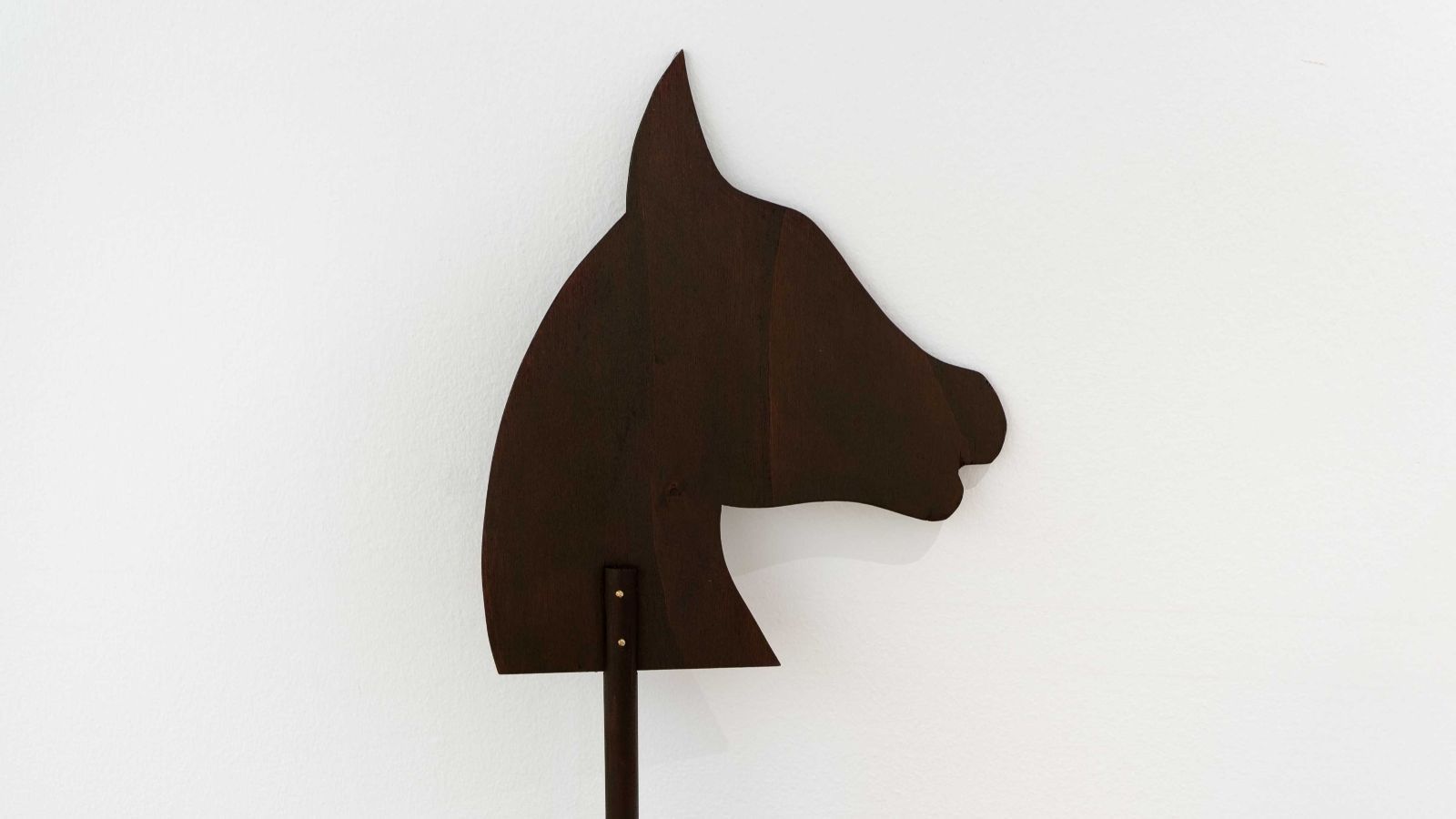 Umriss eines schwarzen Pferdekopfes vor einer weissen Wand