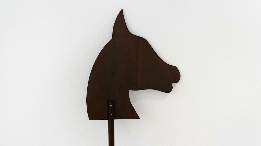 Umriss eines schwarzen Pferdekopfes vor einer weissen Wand